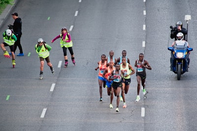 A group of kids running in the grey of the asphalt during the day
